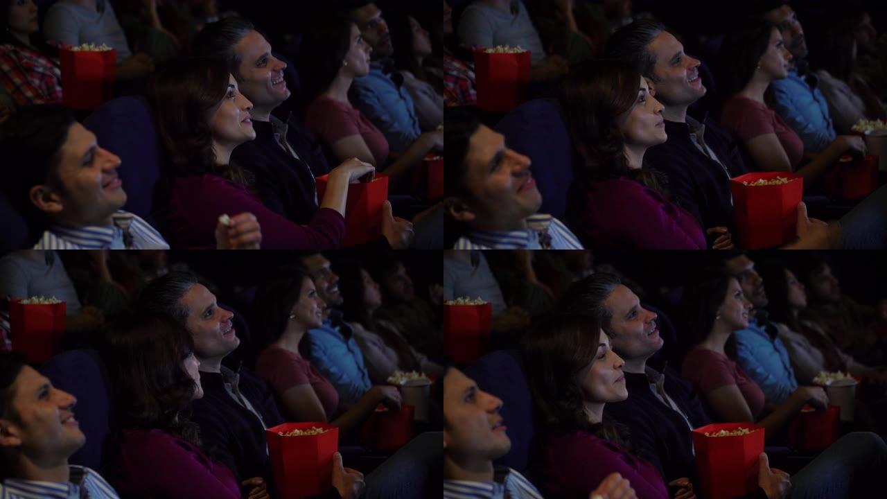电影院里的情侣看电影，享受小吃，看起来很开心