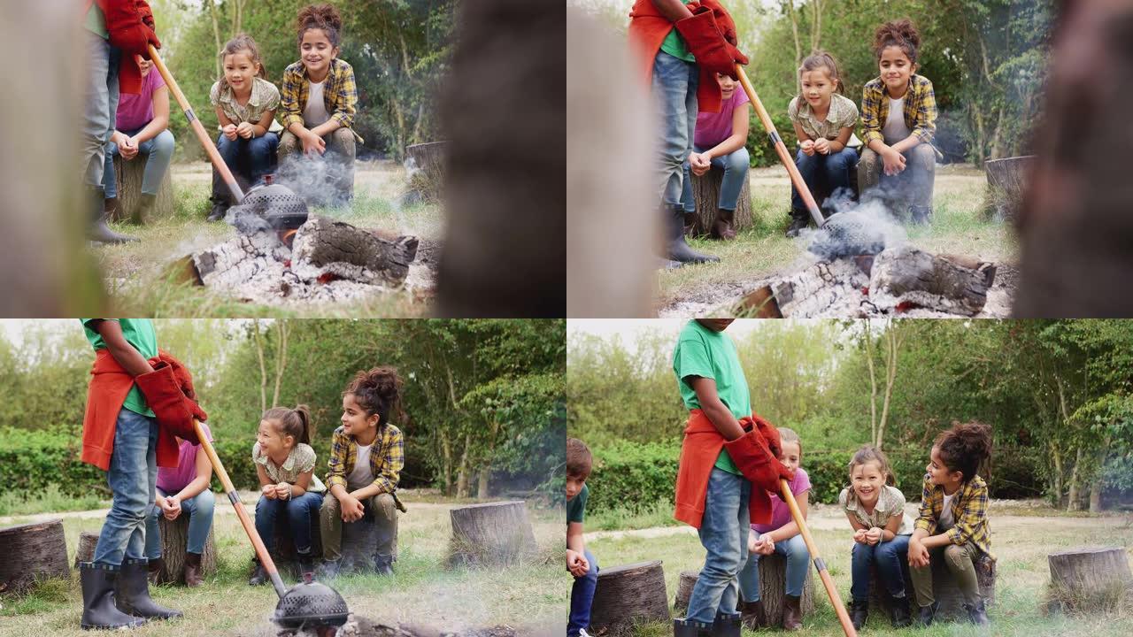 领队带领一组儿童参加户外活动，在营火上做饭