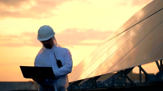 太阳装置和一名男性工程师在日落时在附近工作