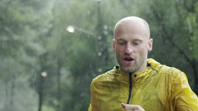 穿着运动服的运动肌肉发达的年轻人在雨中在街上慢跑