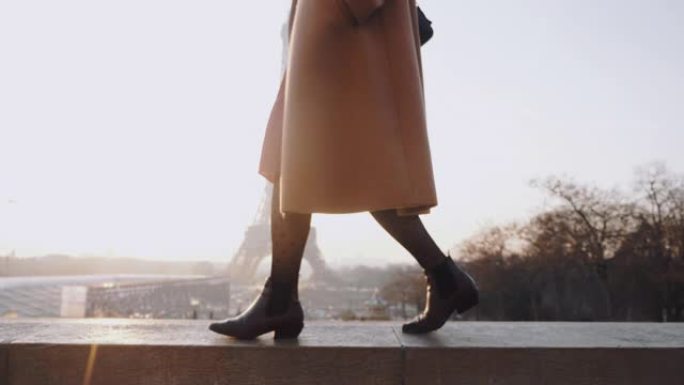 穿着优雅外套的美丽幸福的女人的特写腿走在浪漫的埃菲尔铁塔天空全景巴黎慢动作附近。