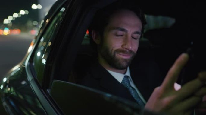 英俊的商人使用他的笔记本电脑在一辆现代汽车旅行期间，一个司机在市中心的夜晚。