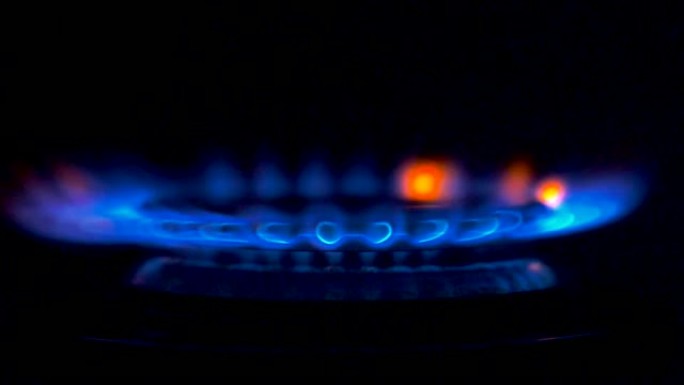燃气灶上点燃的火。从完全黑暗的状态中，蓝色的气体火焰慢慢点燃，带来温暖和热量。慢动作特写镜头