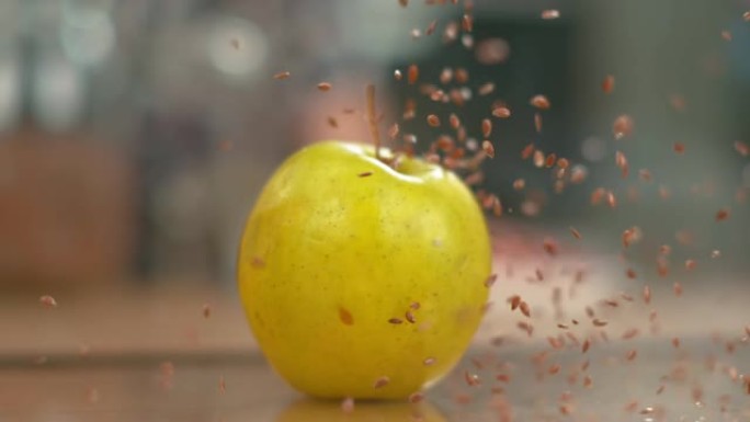 宏观，dop: 微小的棕色亚麻籽从空中掉落到黄色的苹果上。