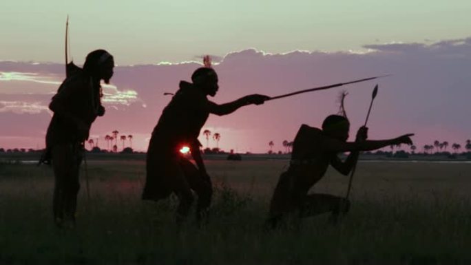 在博茨瓦纳的Makgadikgadi草原上，夕阳下三名桑族人/丛林人穿着传统服饰寻找动物的4K壮观的