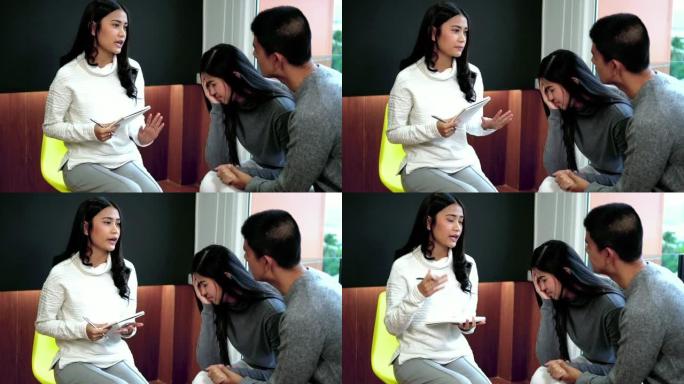 亚洲女性专业心理学家医生的4k慢动作镜头安慰情人夫妇病人关于现代客厅或医院检查室的关系问题、催眠精神
