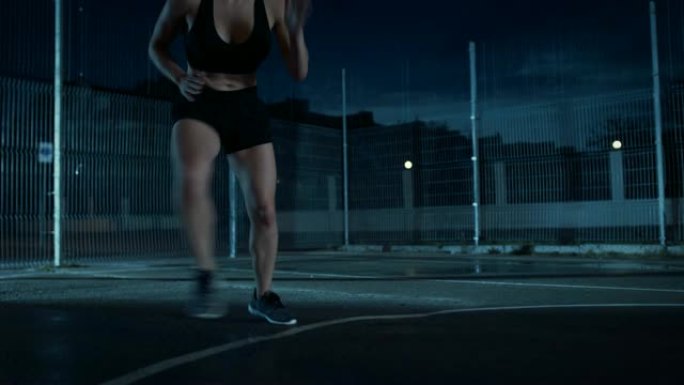 一个美丽的精力充沛的健身女孩做步法跑步训练的特写镜头。她正在一个有围栏的室外篮球场里锻炼身体。居民区
