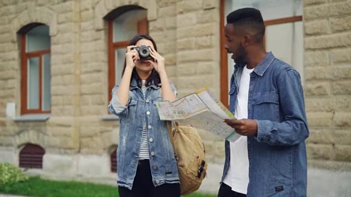 当他迷人的女性朋友站在市中心聊天时，英俊的非洲裔美国男子旅行者正在看地图。