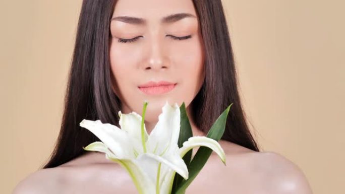 美丽的年轻女子肖像，棕色背景上有花朵。深色女人，奢华妆容。完美的皮肤。美丽女人的水疗肖像，皮肤清晰健