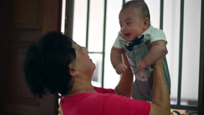 一位亚裔华裔祖母在家中抱着孙子男婴
