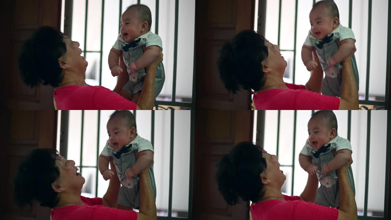 一位亚裔华裔祖母在家中抱着孙子男婴