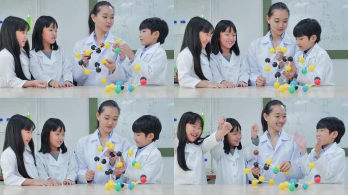 微笑的老师和学生科学家在实验室中观察分子模型。Stem教育。学校的物理实验，孩子们在实验室工作场所构
