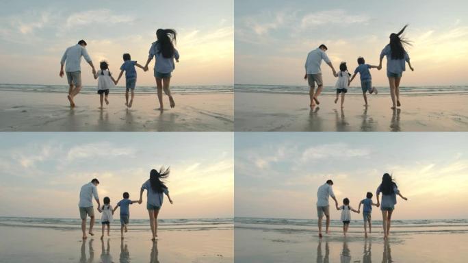 慢动作-亚洲家庭在日落时带着快乐的情感在沙滩上奔跑。家庭、假期和旅行概念。后视图。