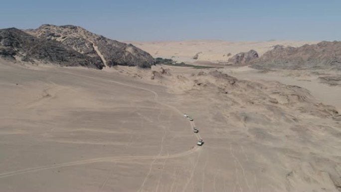 纳米比亚纳米布沙漠骨架海岸上4x4车辆在沙丘和山脉之间行驶的车队的4k鸟瞰图