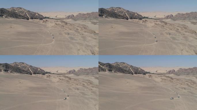 纳米比亚纳米布沙漠骨架海岸上4x4车辆在沙丘和山脉之间行驶的车队的4k鸟瞰图