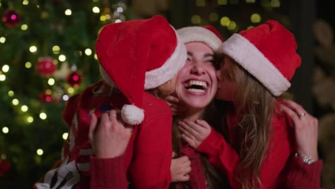 在圣诞节假期庆祝活动中，快乐母亲的慢动作被她的小女儿亲吻。