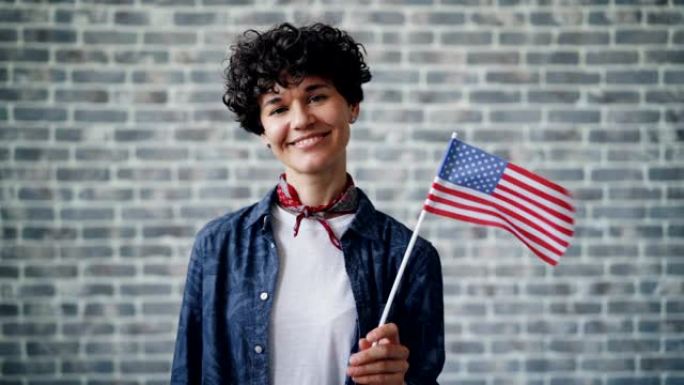 骄傲的美国公民在砖块背景上微笑着举着国旗的慢动作