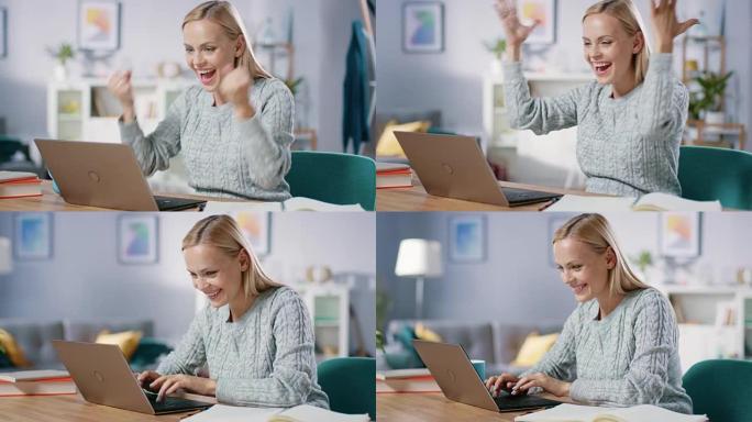 美丽的金发女人坐在客厅的办公桌旁，在笔记本电脑上工作，她用YES手势庆祝成功。女性职业自由职业者在舒