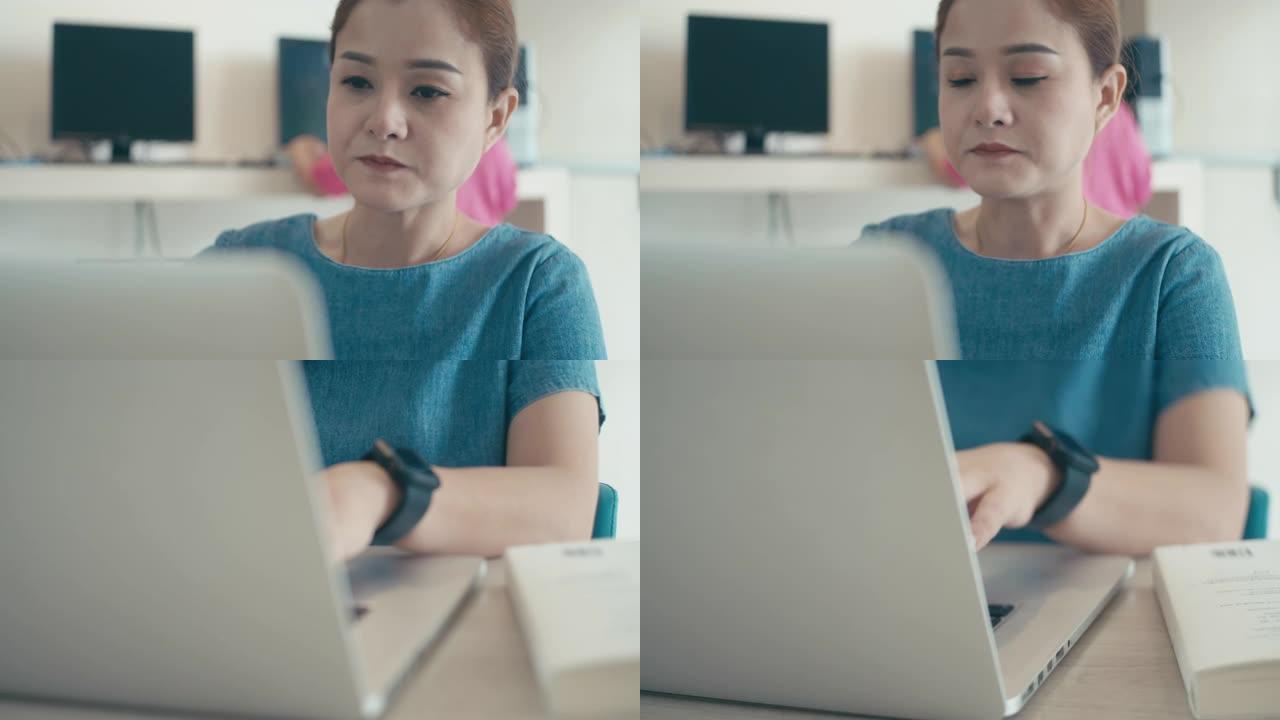 在创业办公室使用笔记本电脑和喝冰咖啡的年轻女性