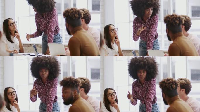 千禧一代黑人妇女站在会议室里向富有创造力的同事展示，倾斜镜头