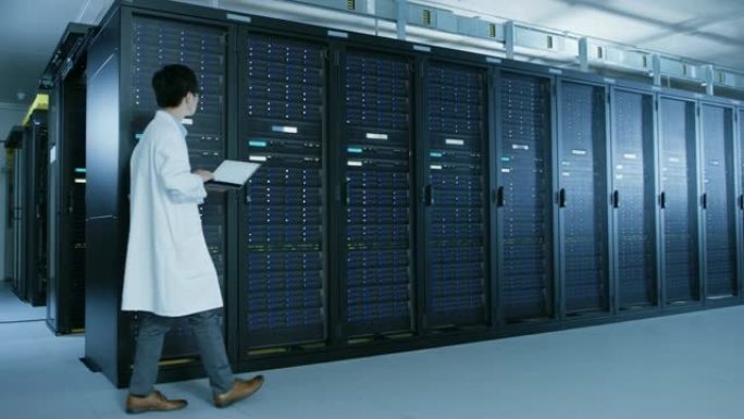 在数据中心: 穿着白大褂的男性IT专家走在一排服务器机架旁边，使用笔记本电脑运行维护诊断工具，进行控