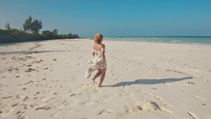穿着长裙的SLO MO女人在美丽的海滩上奔跑