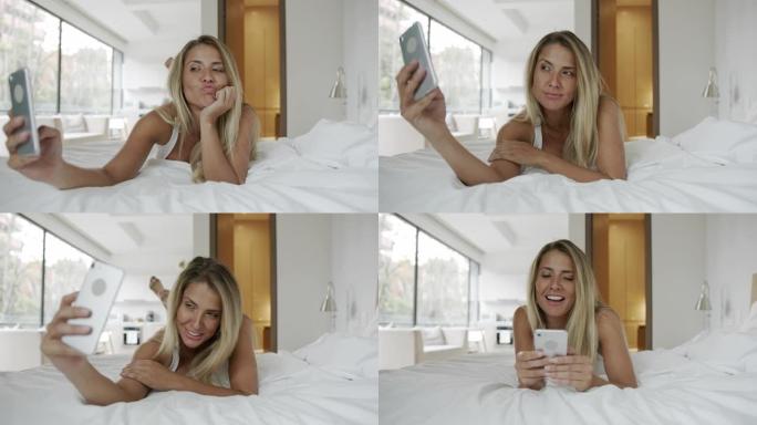 美丽的女人在床上放松，开心地用智能手机微笑自拍