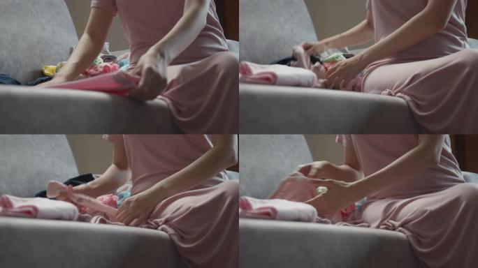 妈妈坐在沙发上折叠婴儿衣服
