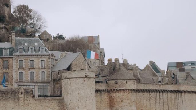 法国国旗在雄伟的古代圣米歇尔山挥舞的背景照片，著名的岛屿要塞镇慢动作。