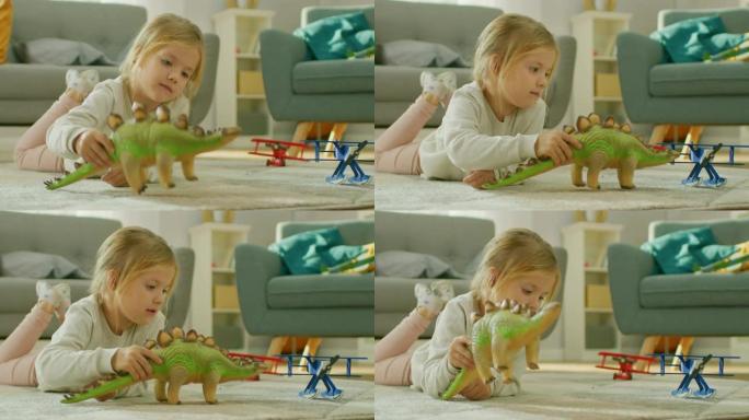 可爱的小女孩金发躺在家里的地毯上，玩玩具恐龙和飞机。快乐的孩子在阳光明媚的客厅里玩玩具。