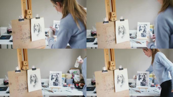 女少年艺术家在木炭中的狗的绘画图片上喷涂漆器固定剂