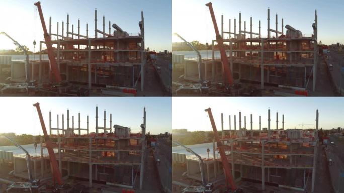 鸟瞰图: 工业/商业物业建筑工地。日出中的机械和摩天大楼混凝土模板框架