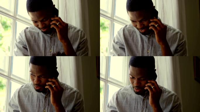 在舒适的家庭中，年轻的黑人男子在手机上聊天的前视图4k