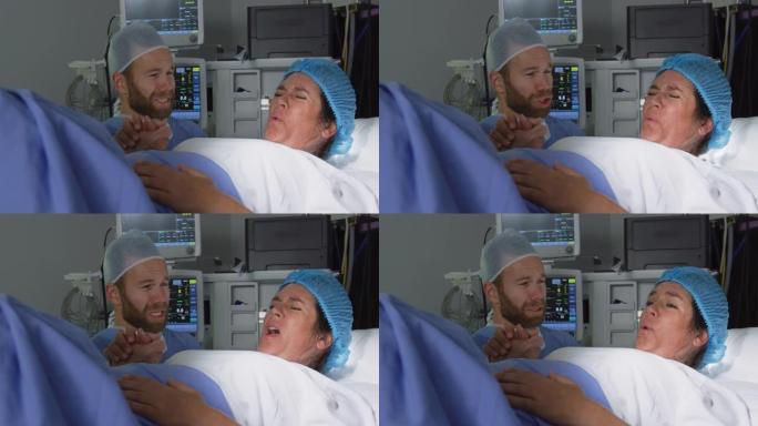 高加索男子在医院手术室分娩时安慰孕妇的前视图