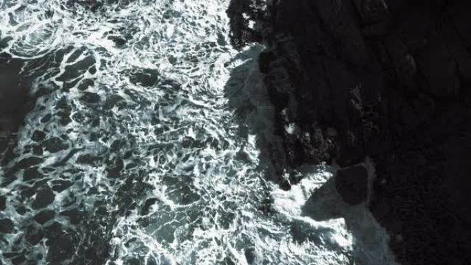 美丽的海洋，大浪在悬崖和岩石海岸上滚动。海浪撞击岩石的风景摄影。黑白自上而下的空中无人机镜头