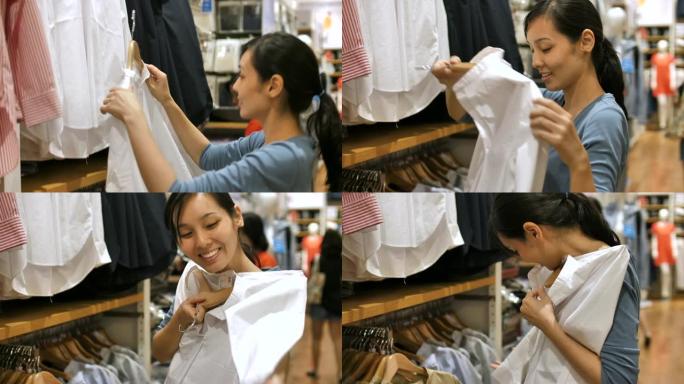 年轻的亚洲妇女站在室内的服装店购物，选择衬衫