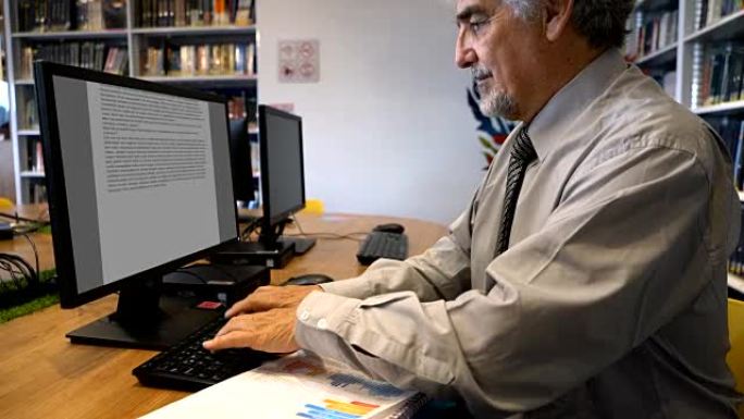 成人老师在图书馆使用计算机处理文档