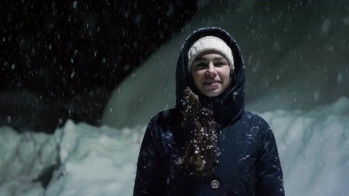 当雪从天而降时，一个美丽的女人在夜晚停在灯光下，开始玩耍，呼吸着干净的空气，在大自然中跳舞。