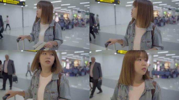 慢动作 -- 快乐的亚洲女人在国际机场登机口登机时，使用手推车或手推车和许多行李走在航站楼大厅。