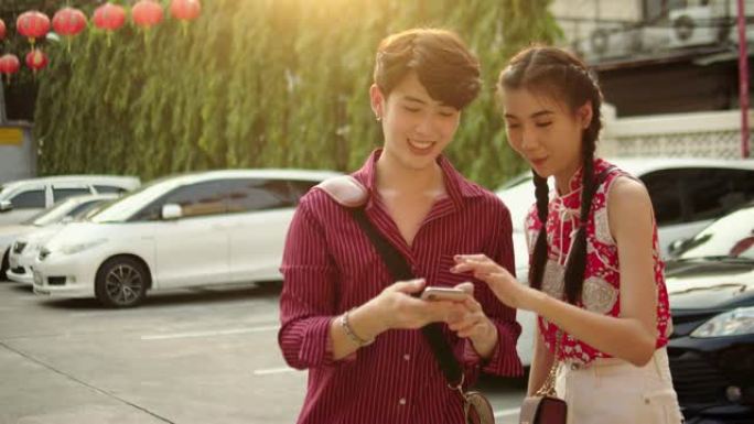 年轻的亚洲夫妇在城市街道上使用智能手机进行自画像