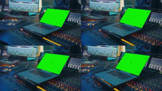 现代音乐录音室控制台，配有绿屏色度键笔记本电脑、均衡器、混音器和其他专业设备。切换器、按钮、推子、滑