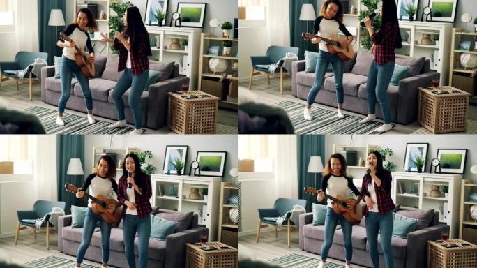 可爱的年轻女士亚洲和非裔美国人正在用遥控器唱歌，在家里弹吉他放松，表达积极的情绪。友谊和有趣的概念。
