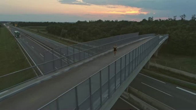 黄昏时在高速公路上的桥上的空中女人