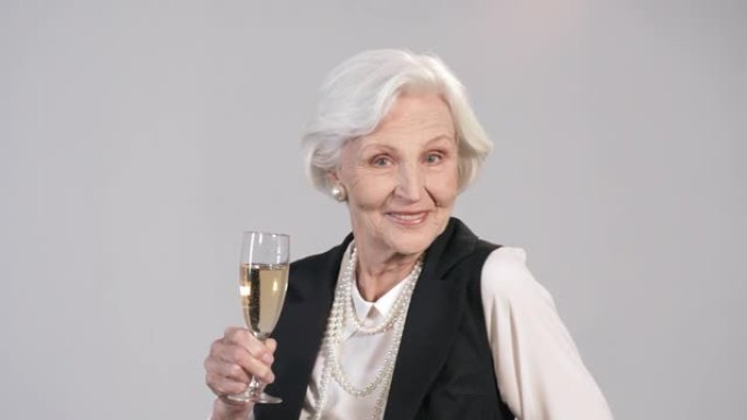 美丽的老年妇女与一杯香槟跳舞