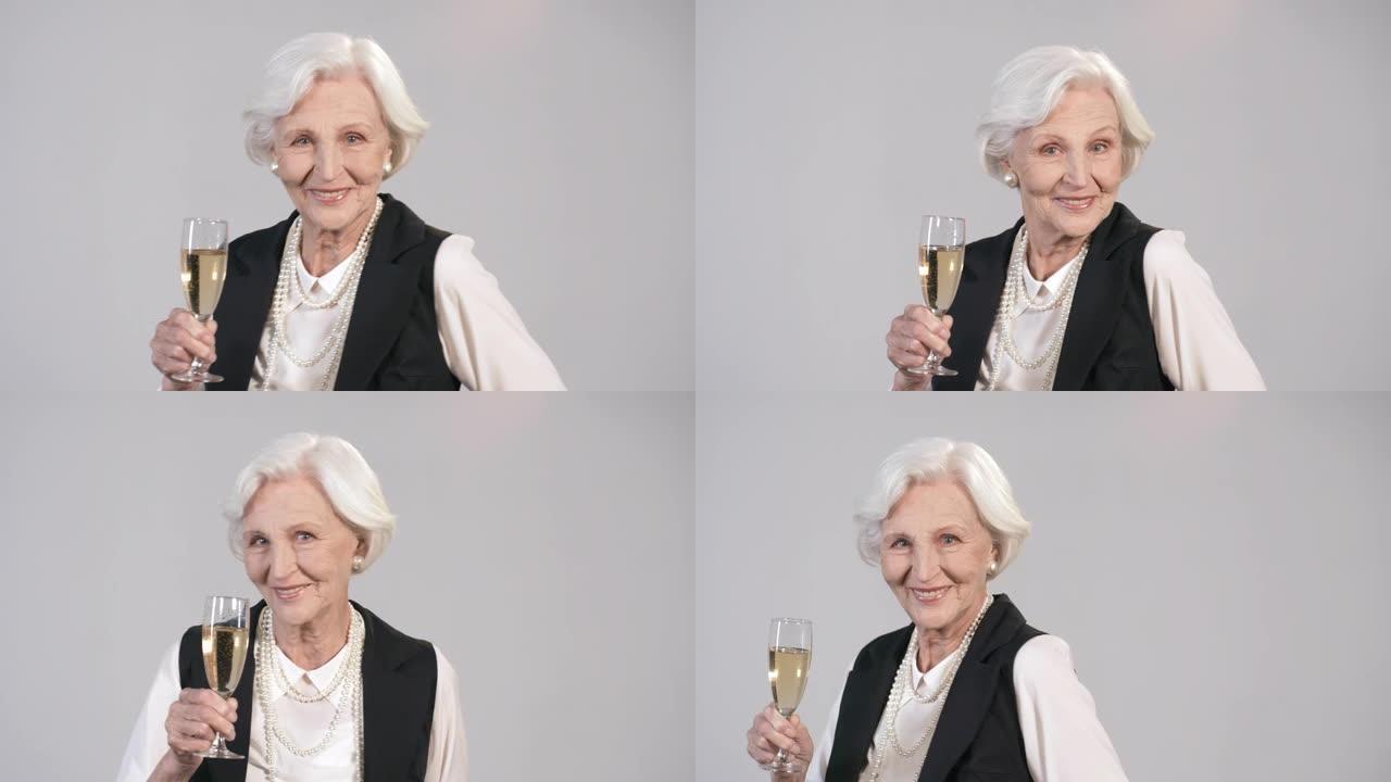 美丽的老年妇女与一杯香槟跳舞