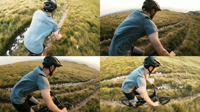 在阳光明媚的日子里，男子在高山上绿草如茵的自行车道上骑自行车