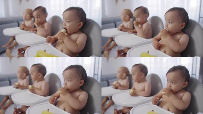 混血三胞胎婴儿坐在高脚椅上吃香蕉
