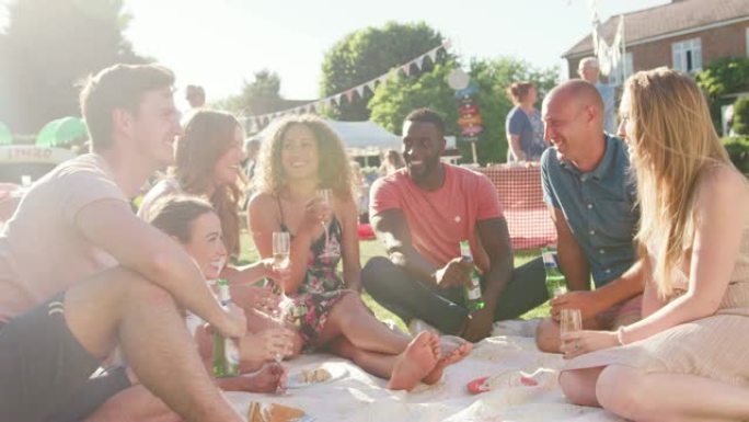 一群朋友坐在夏日花园的地毯上吃饭和喝酒-慢动作拍摄