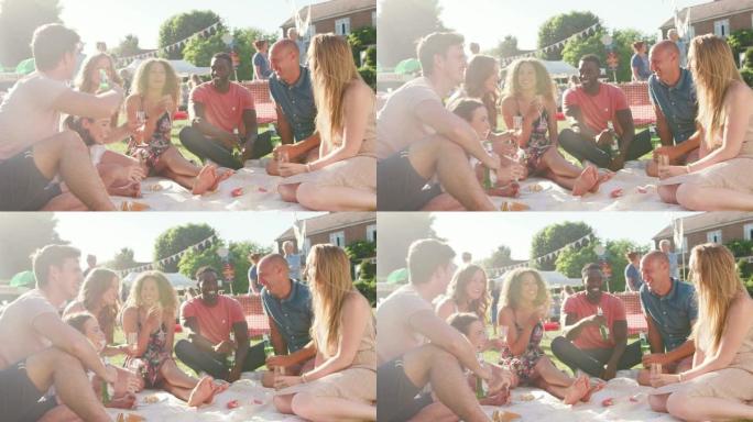 一群朋友坐在夏日花园的地毯上吃饭和喝酒-慢动作拍摄