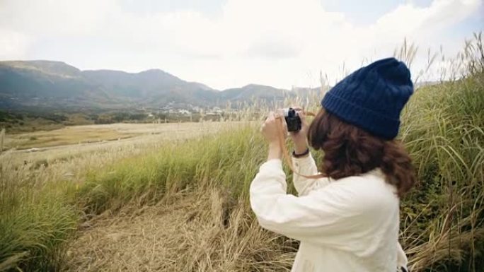 亚洲旅游女子用相机在山腰拍照